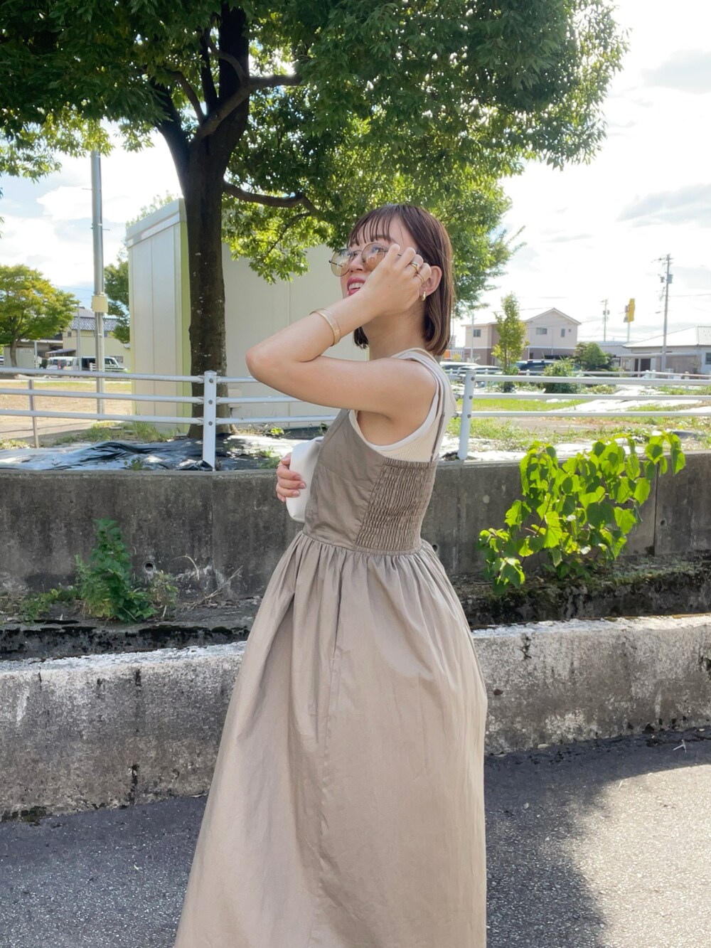 ベージュ系のワンピース、ホワイト系のハンドバッグ、ブラック系のサンダルを着用したレディースの夏コーディネートの3枚目の写真