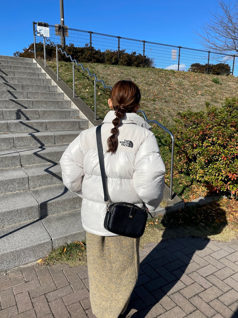 ホワイト系のダウンジャケット/コート、イエロー系のワンピース、ブラック系のブーツを着用したレディースの冬コーディネートの2枚目の写真