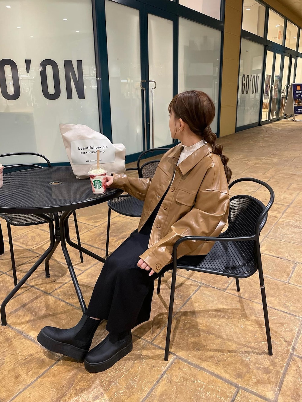 ブラウン系のその他アウター、ホワイト系のニット/セーター、ブラック系のブーツを着用したレディースの秋コーディネートの2枚目の写真