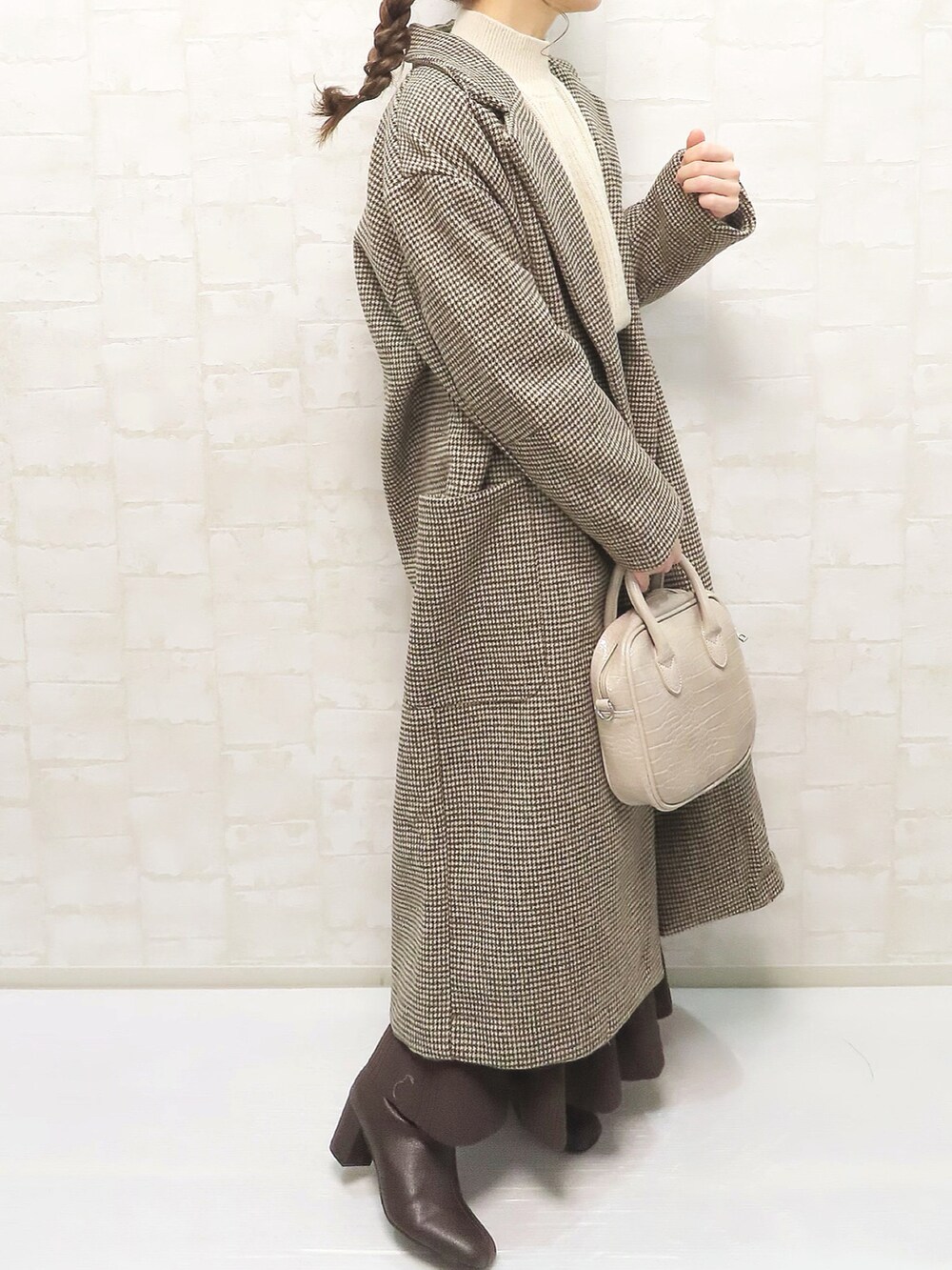 ブラウン系のチェスターコート、ベージュ系のニット/セーター、ブラウン系のスカートを着用したレディースの冬コーディネートの4枚目の写真