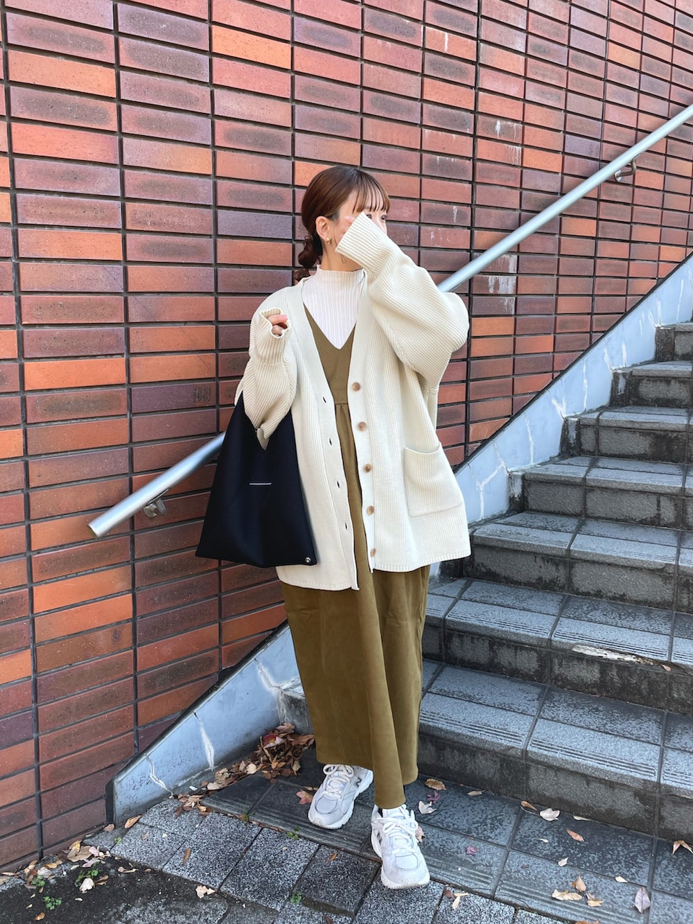グリーン系のジャンパースカート、ホワイト系のニット/セーター、ホワイト系のカーディガン/ボレロを着用したレディースの冬コーディネートの4枚目の写真