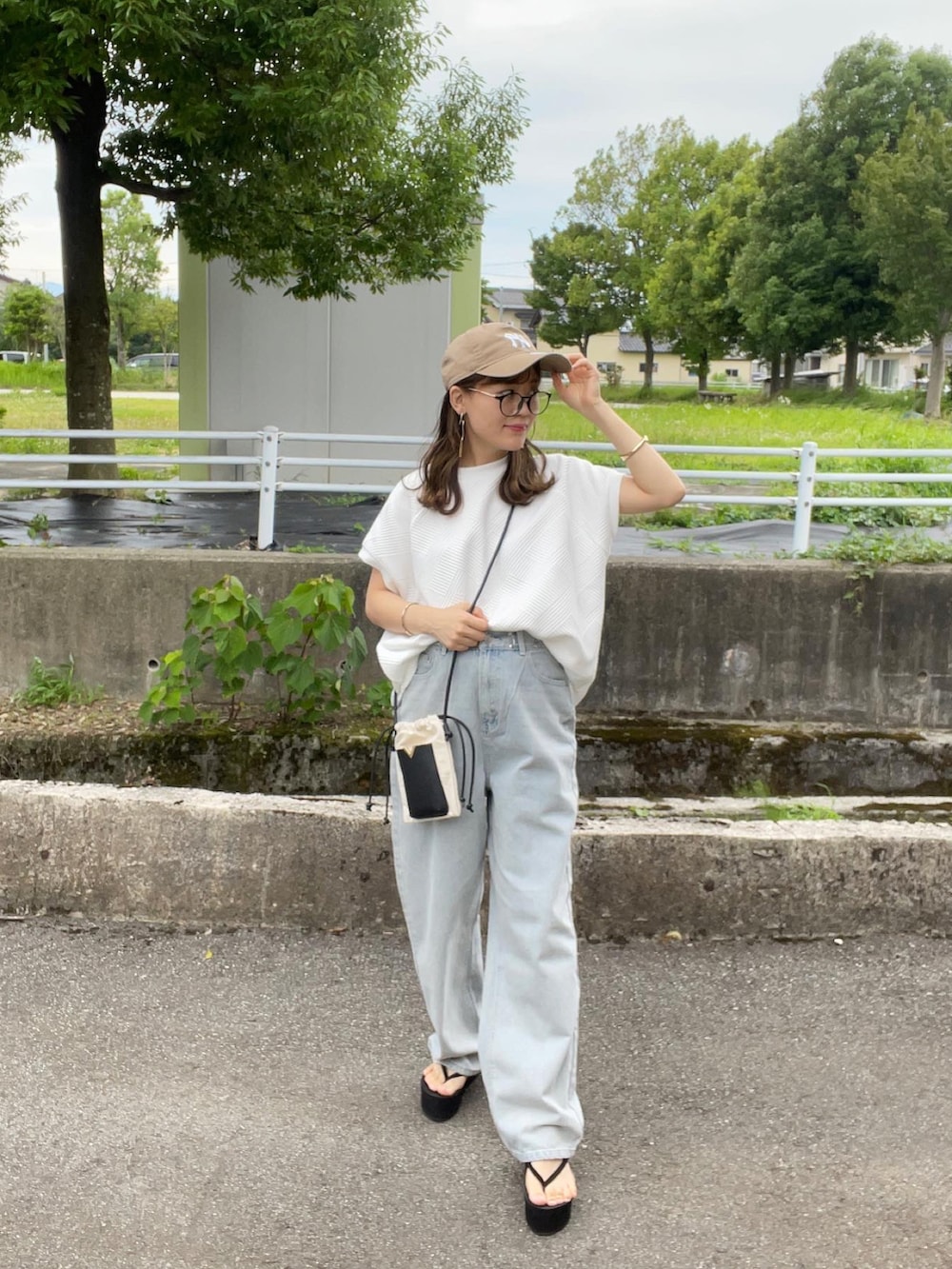 ホワイト系のTシャツ/カットソー、ブルー系のデニムパンツ、ホワイト系のショルダーバッグを着用したレディースの夏コーディネートの2枚目の写真