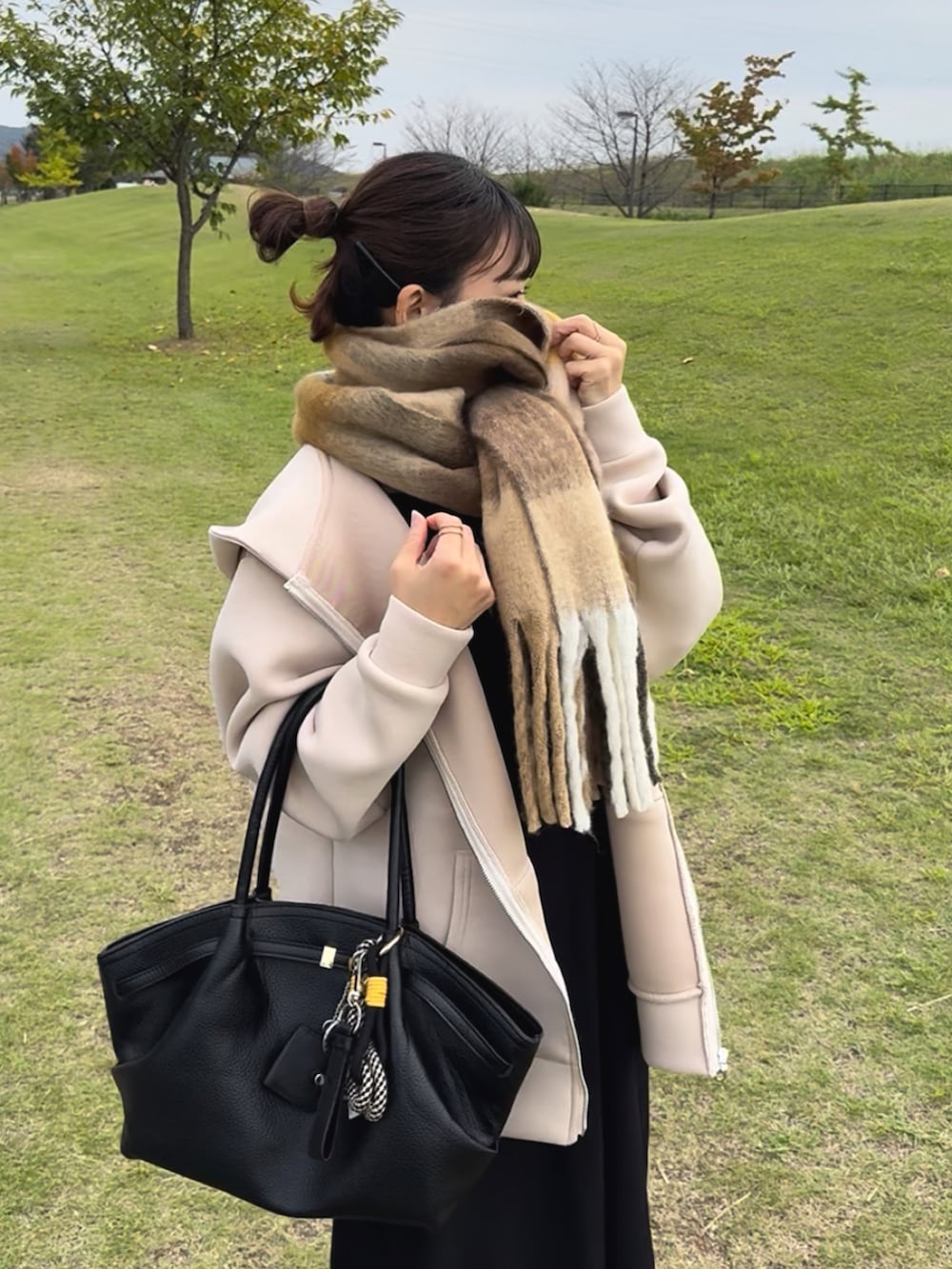 ベージュ系のパーカー、ブラック系のワンピース、ホワイト系のスニーカーを着用したレディースの冬コーディネートの2枚目の写真