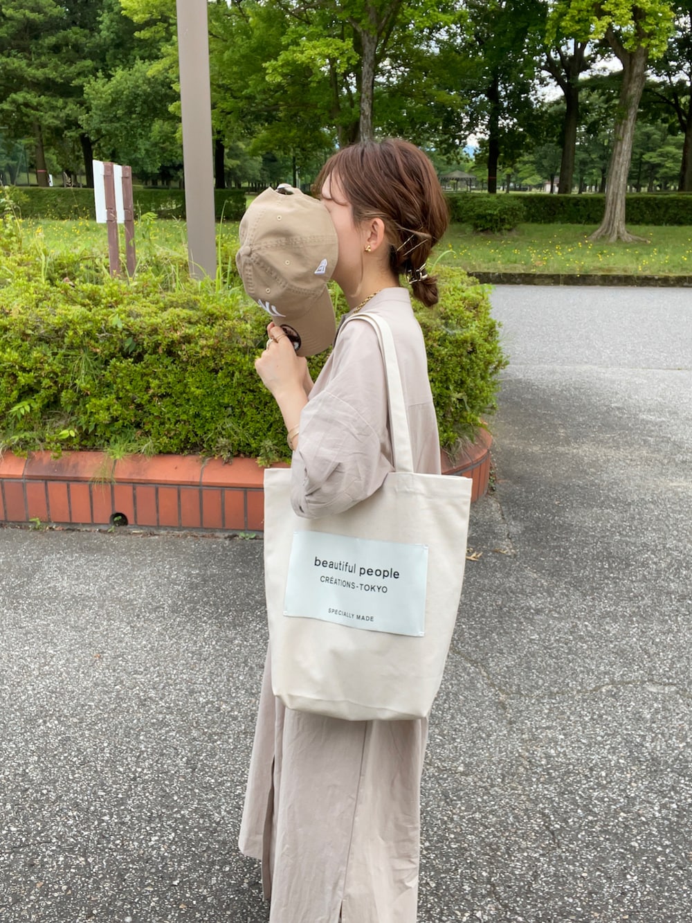 グレー系のシャツワンピース、ホワイト系のトートバッグ、ホワイト系のサンダルを着用したレディースの夏コーディネートの2枚目の写真