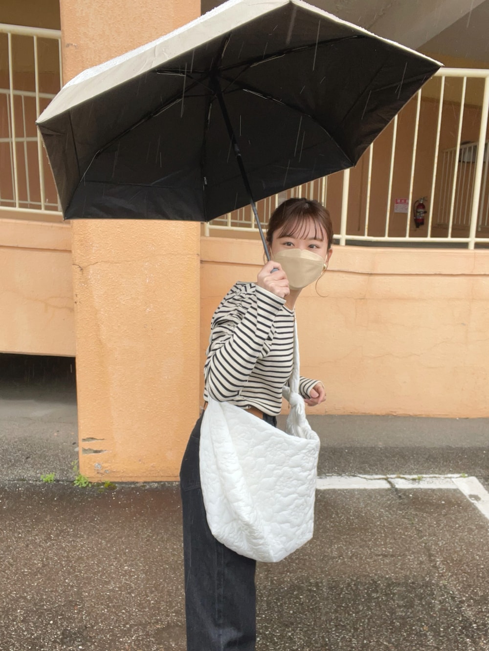 ブラック系のTシャツ/カットソー、ブラック系のデニムパンツ、ホワイト系のショルダーバッグを着用したレディースの春コーディネートの2枚目の写真