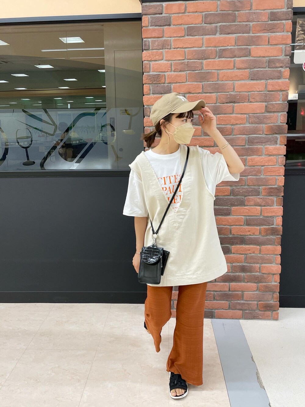 ブラウン系のその他パンツ、ホワイト系のベスト、オレンジ系のTシャツ/カットソーを着用したレディースの夏コーディネートの3枚目の写真