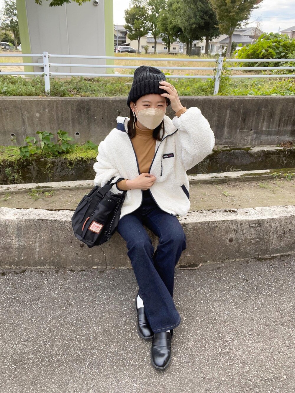 ホワイト系のブルゾン、イエロー系のトップス、ブルー系のデニムパンツを着用したレディースの冬コーディネートの2枚目の写真