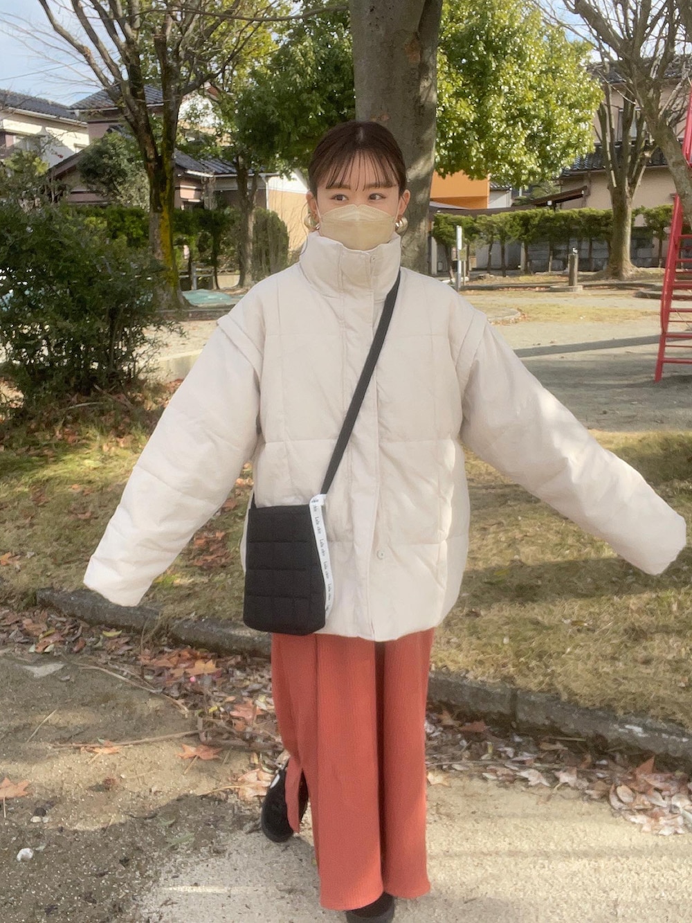 オレンジ系のワンピース、ホワイト系のニット/セーター、ブラック系のショルダーバッグを着用したレディースの冬コーディネートの5枚目の写真