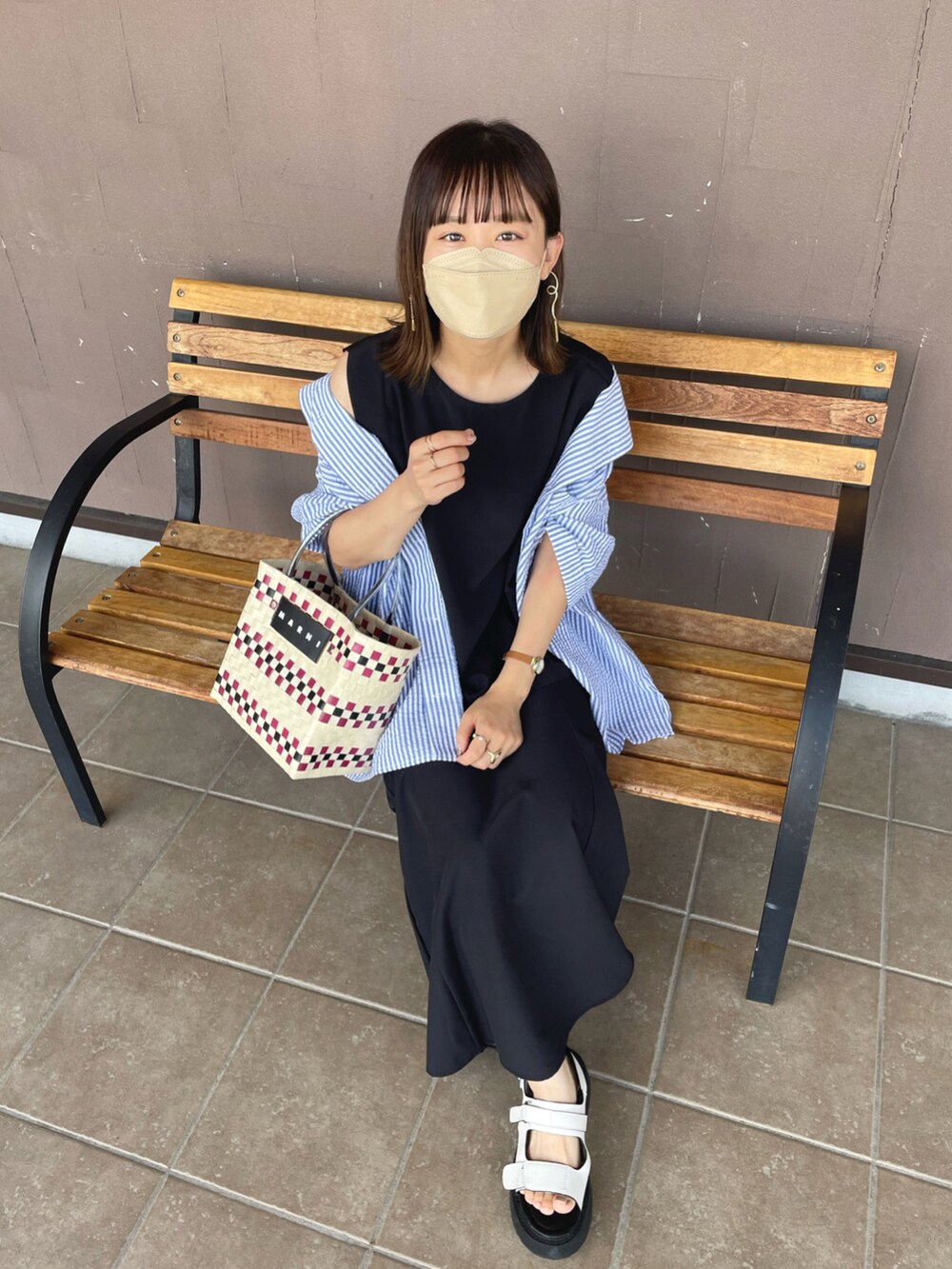 ブラック系のセットアップ、ベージュ系のサンダル、ホワイト系のかごバッグを着用したレディースの夏コーディネートの2枚目の写真