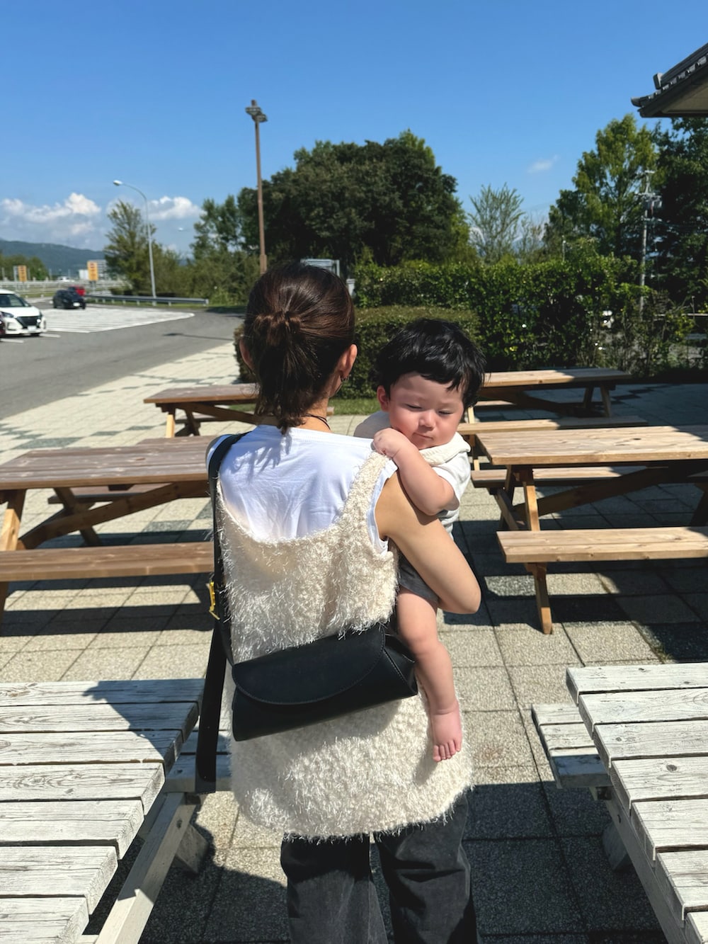 ホワイト系のベスト、ブラック系のショルダーバッグ、ブラック系のデニムパンツを着用したレディースの秋コーディネートの4枚目の写真