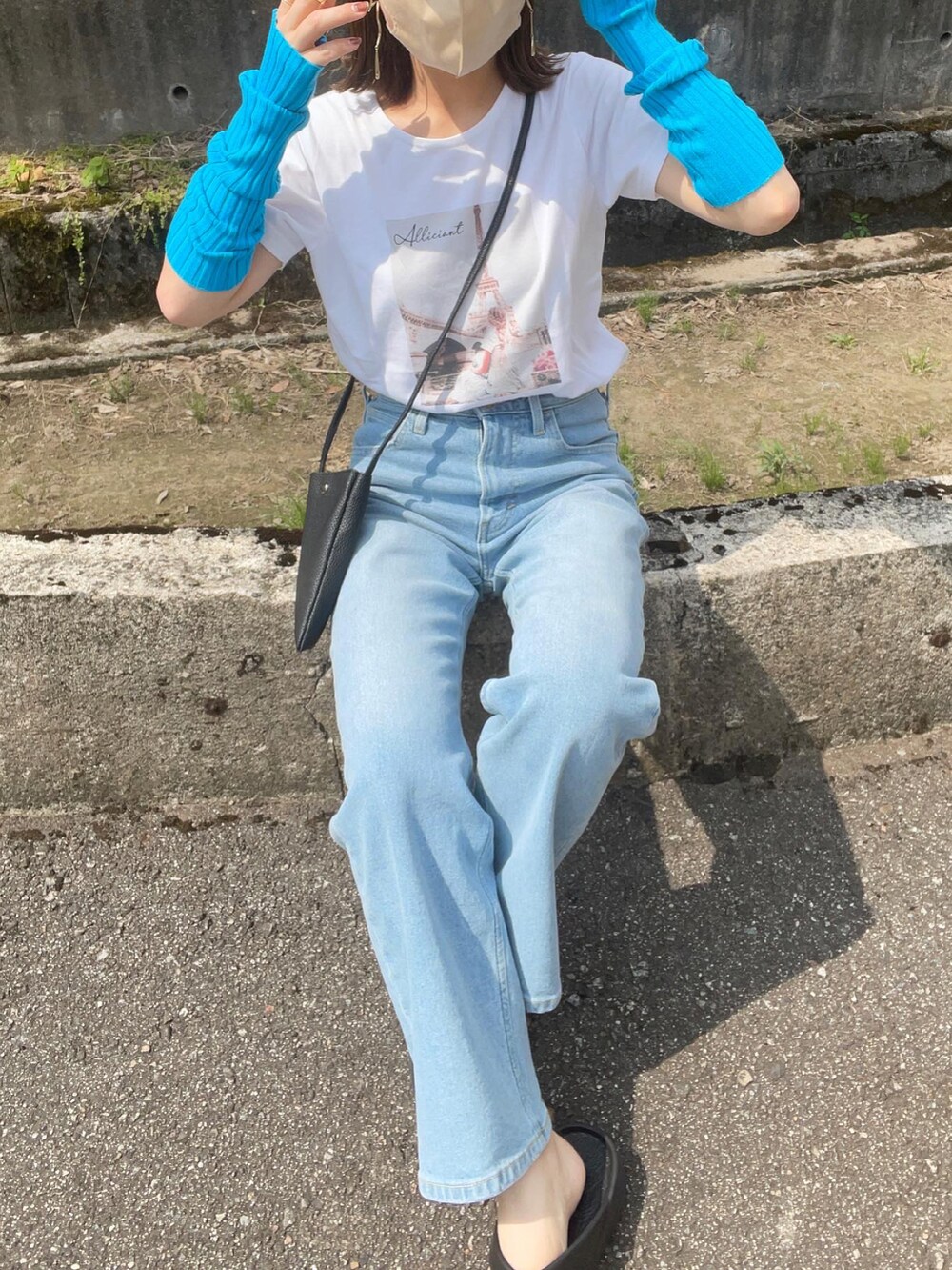 ブルー系のデニムパンツ、ホワイト系のTシャツ/カットソー、ブラック系のショルダーバッグを着用したレディースの夏コーディネートの2枚目の写真