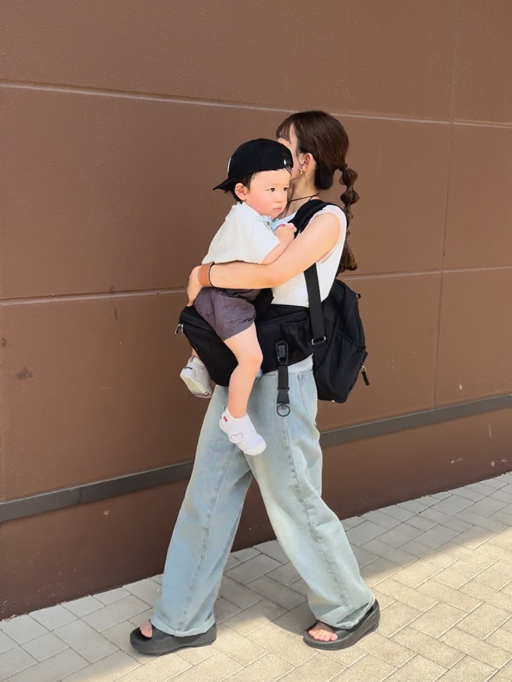 ホワイト系のトップス、ブルー系のデニムパンツ、ブラック系のサンダルを着用したレディースの夏コーディネートの2枚目の写真