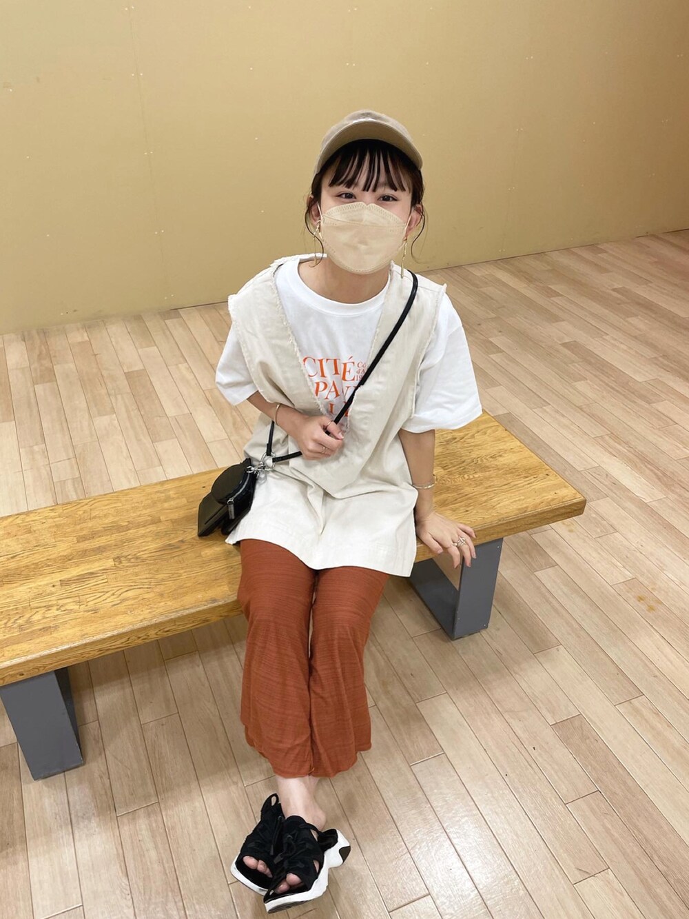 ブラウン系のその他パンツ、ホワイト系のベスト、オレンジ系のTシャツ/カットソーを着用したレディースの夏コーディネートの2枚目の写真