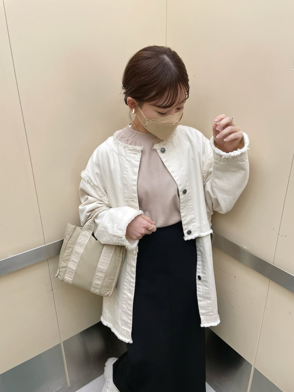 ベージュ系のTシャツ/カットソー、ホワイト系のデニムジャケット、ブラック系のスカートを着用したレディースの春コーディネートの2枚目の写真