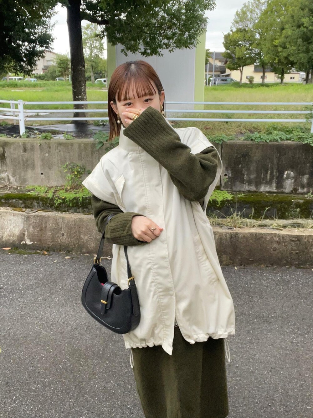 ホワイト系のミリタリージャケット、グリーン系のワンピース、ブラック系のバッグを着用したレディースの秋コーディネートの2枚目の写真