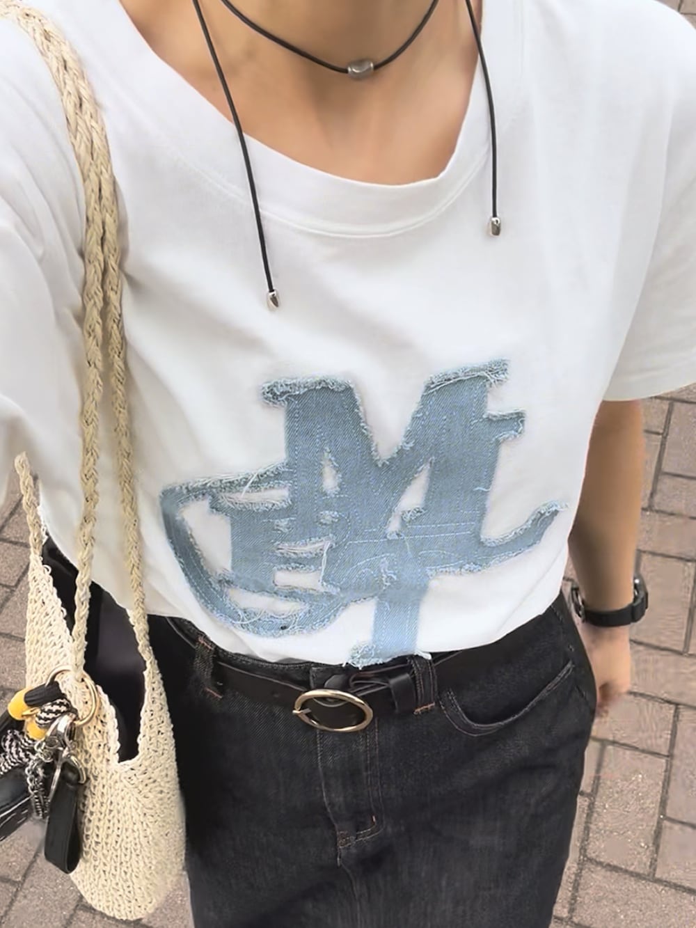 ホワイト系のTシャツ/カットソー、ブラック系のデニムスカート、ベージュ系のかごバッグを着用したレディースの夏コーディネートの5枚目の写真