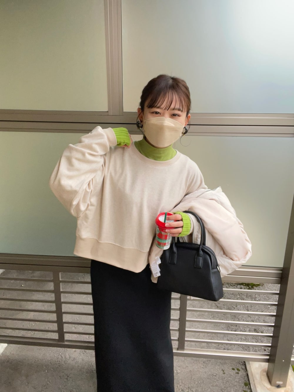 ベージュ系のスウェット、グリーン系のニット/セーター、ホワイト系のダウンベストを着用したレディースの秋コーディネートの2枚目の写真