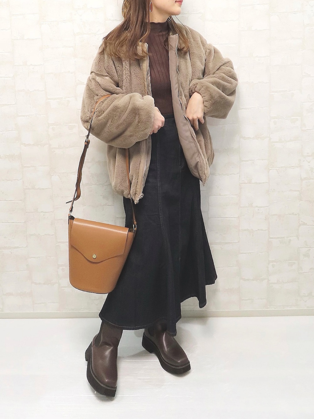 ブラウン系のブルゾン、ブラウン系のニット/セーター、ブルー系のデニムスカートを着用したレディースの秋コーディネートの2枚目の写真