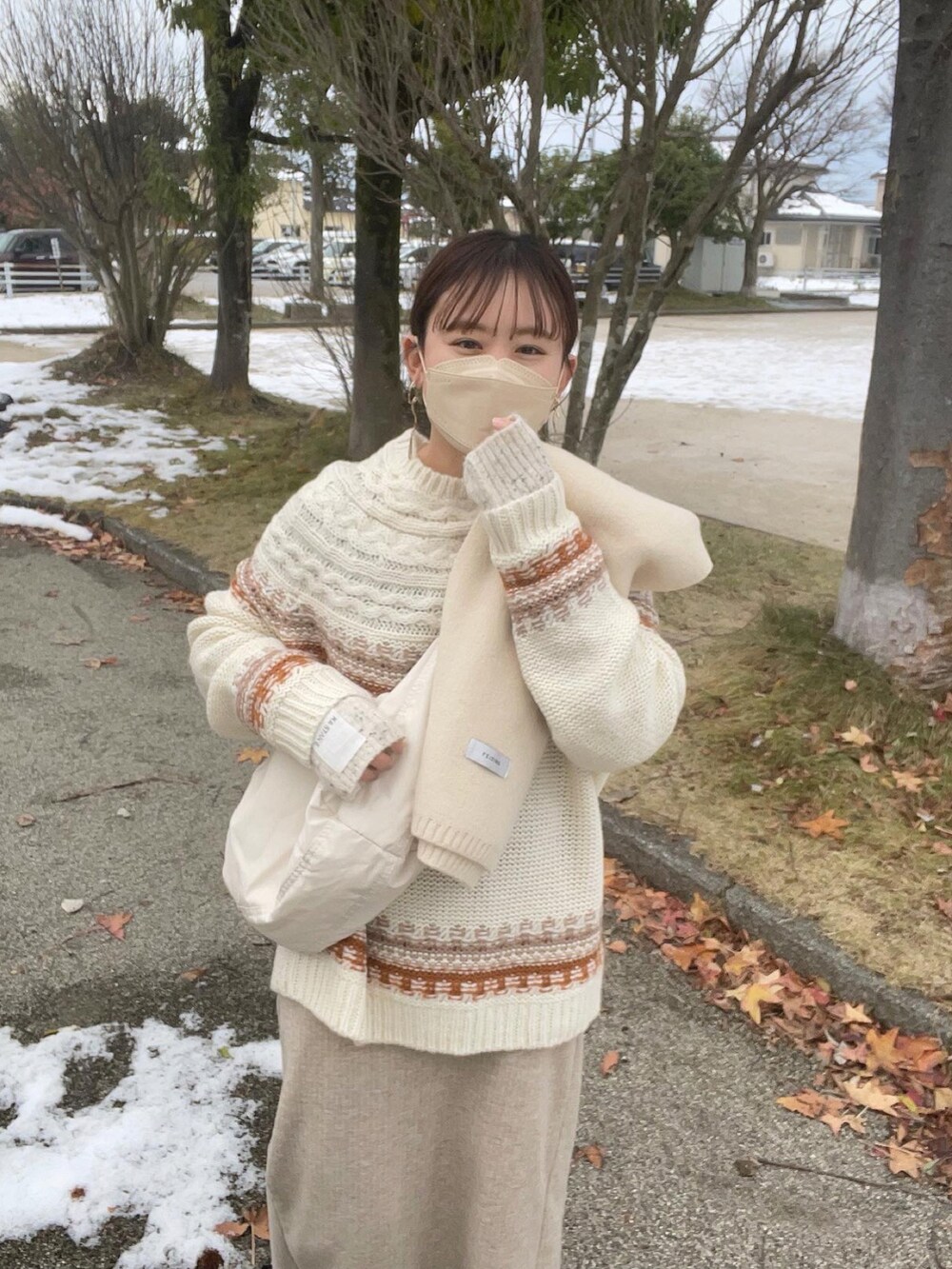 ブラウン系のニット/セーター、ホワイト系のショルダーバッグ、ベージュ系のスカートを着用したレディースの冬コーディネートの5枚目の写真