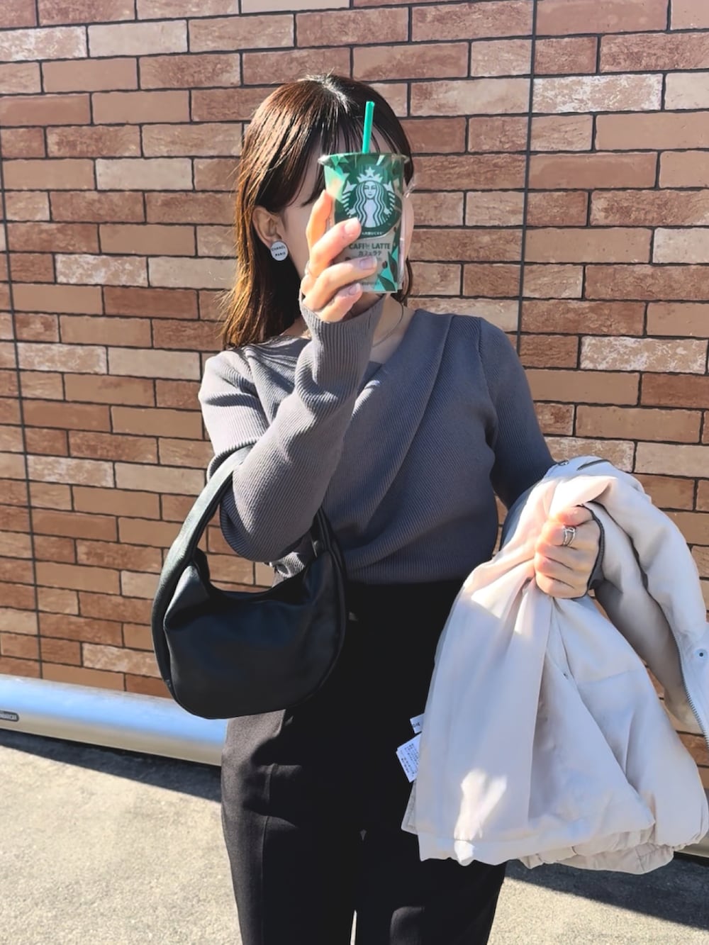 グレー系のニット/セーター、ホワイト系のダウンベスト、ブラック系のスラックスを着用したレディースの冬コーディネートの4枚目の写真