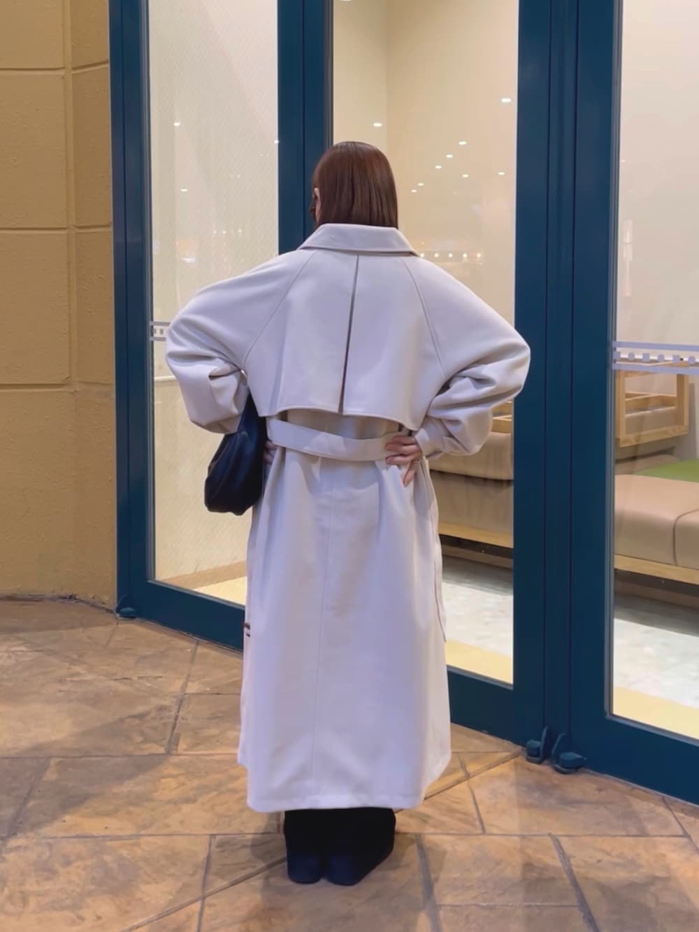 ホワイト系のステンカラーコート、グレー系のニット/セーター、ブラック系のハンドバッグを着用したレディースの冬コーディネートの4枚目の写真