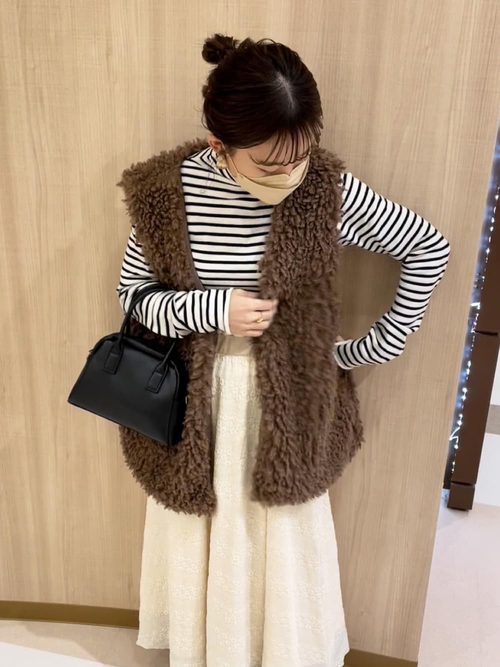 ブラウン系のベスト、ホワイト系のニット/セーター、ベージュ系のスカートを着用したレディースの冬コーディネートの2枚目の写真