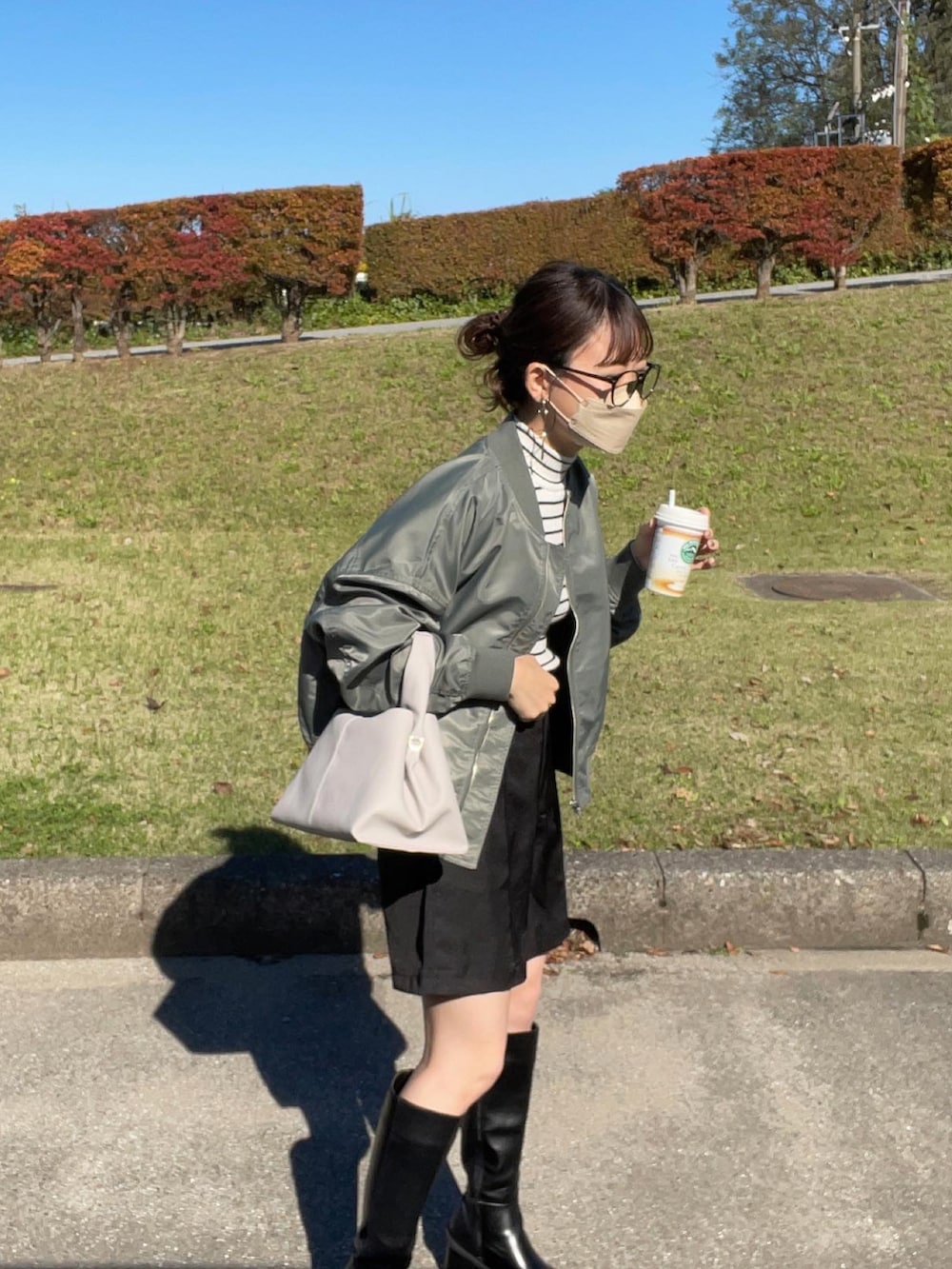 グリーン系のブルゾン、ホワイト系のニット/セーター、ブラック系のスラックスを着用したレディースの秋コーディネートの2枚目の写真