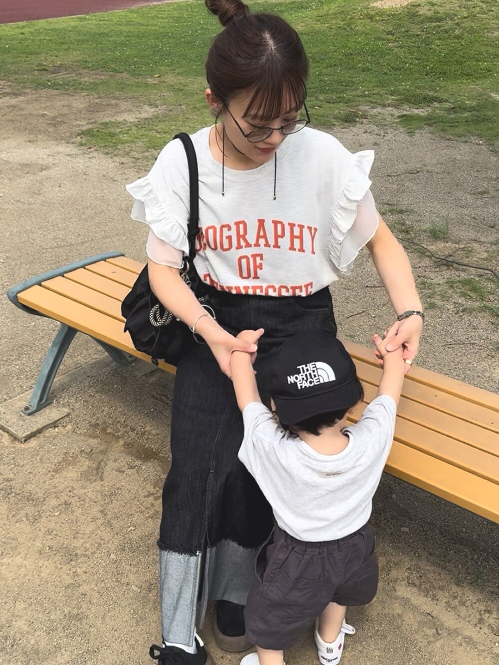 ベージュ系のTシャツ/カットソー、ブラック系のデニムスカート、ブラック系のバッグを着用したレディースの夏コーディネートの2枚目の写真
