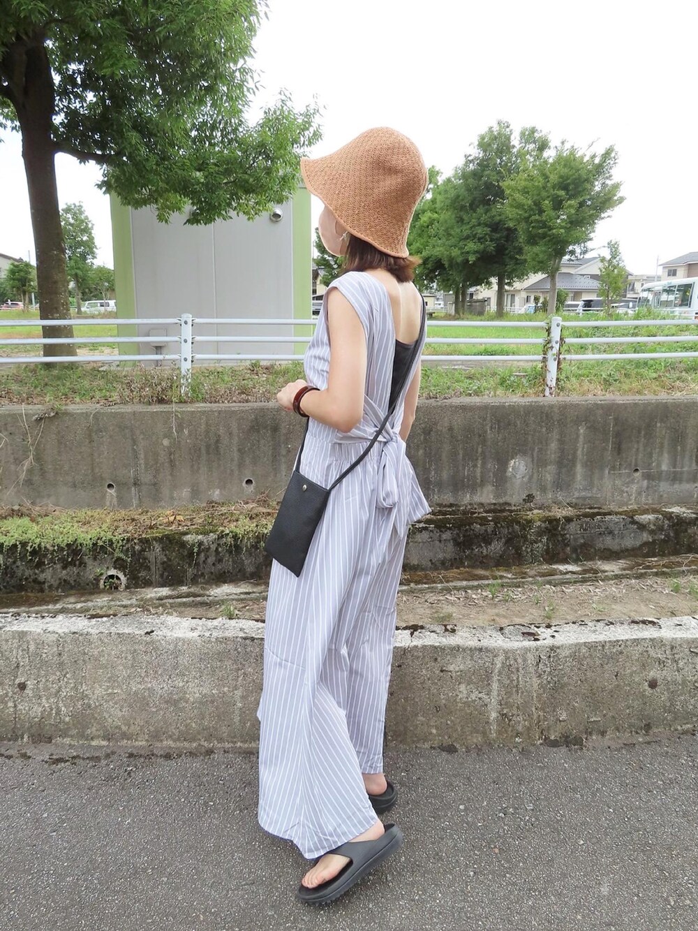 グレー系のワンピース、ブラック系のショルダーバッグ、ブラック系のサンダルを着用したレディースの夏コーディネートの3枚目の写真