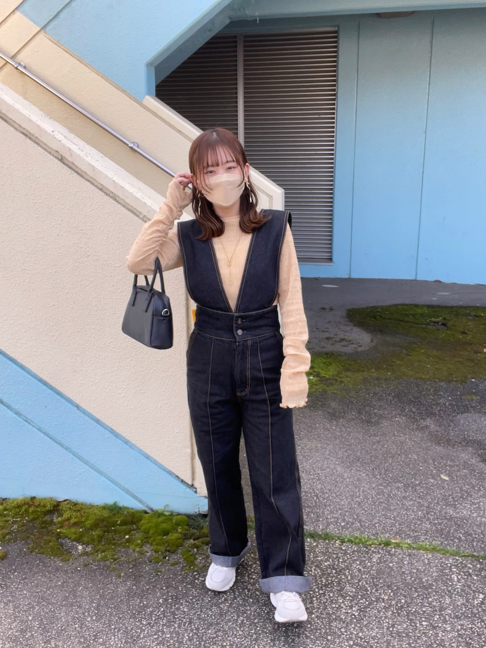 オレンジ系のTシャツ/カットソー、ブラック系のサロペット/オーバーオール、ホワイト系のスニーカーを着用したレディースの春コーディネートの2枚目の写真