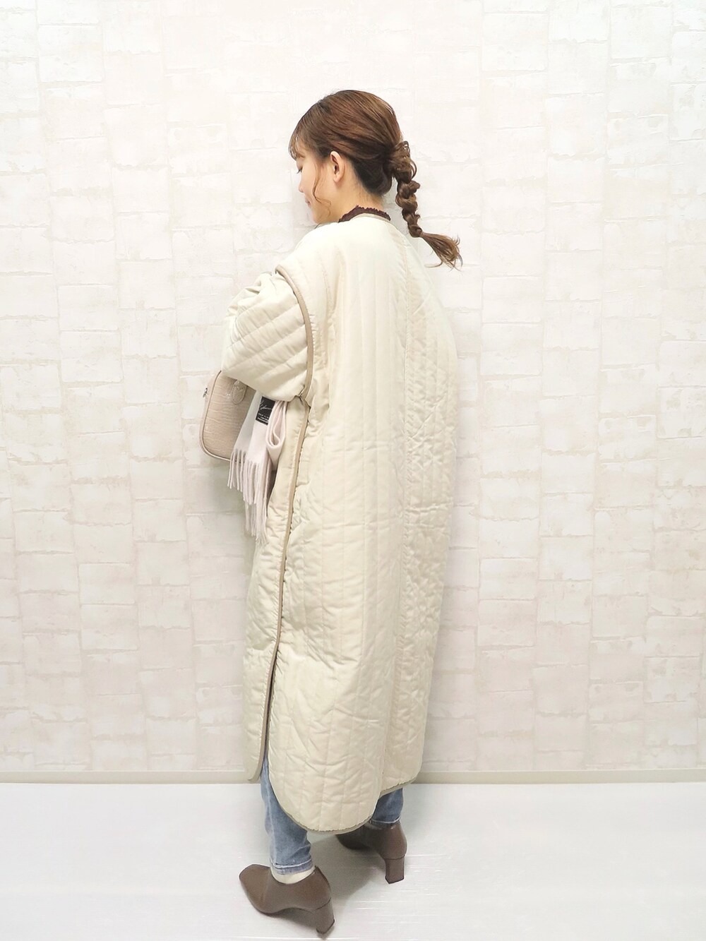 ベージュ系のノーカラーコート、ブラウン系のニット/セーター、ベージュ系のブーツを着用したレディースの冬コーディネートの2枚目の写真