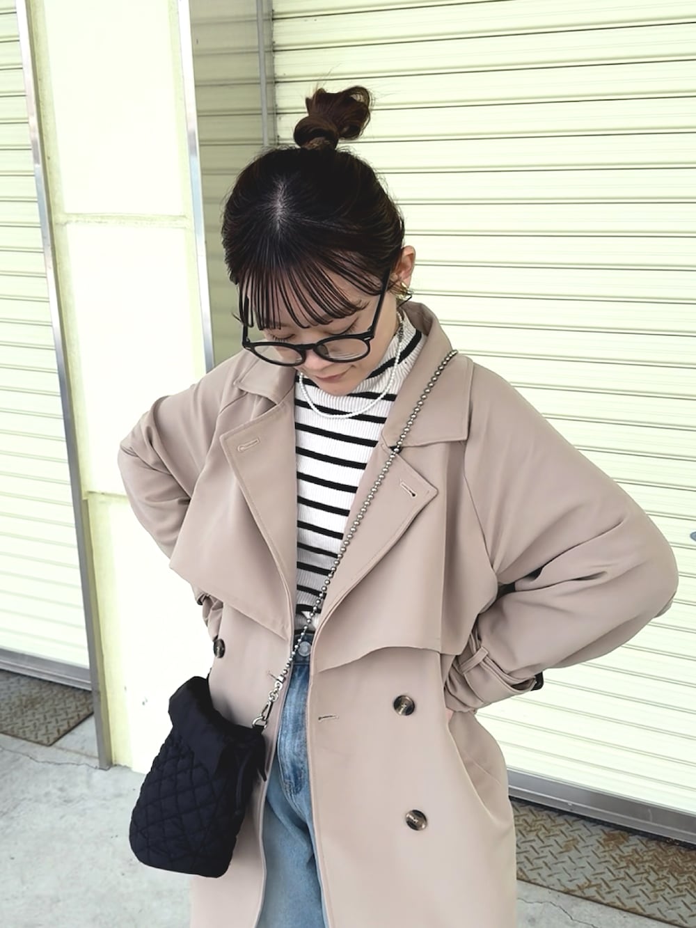 イエロー系のトレンチコート、グレー系のニット/セーター、ブルー系のデニムパンツを着用したレディースの冬コーディネートの2枚目の写真