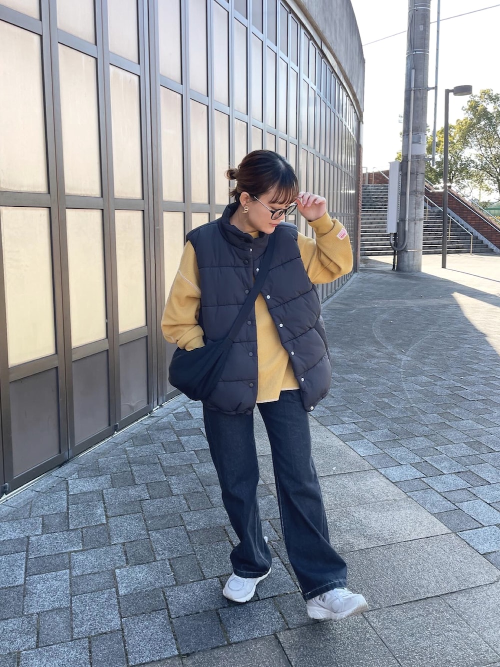 ブラック系のダウンベスト、イエロー系のTシャツ/カットソー、ブラック系のデニムパンツを着用したレディースの冬コーディネートの4枚目の写真