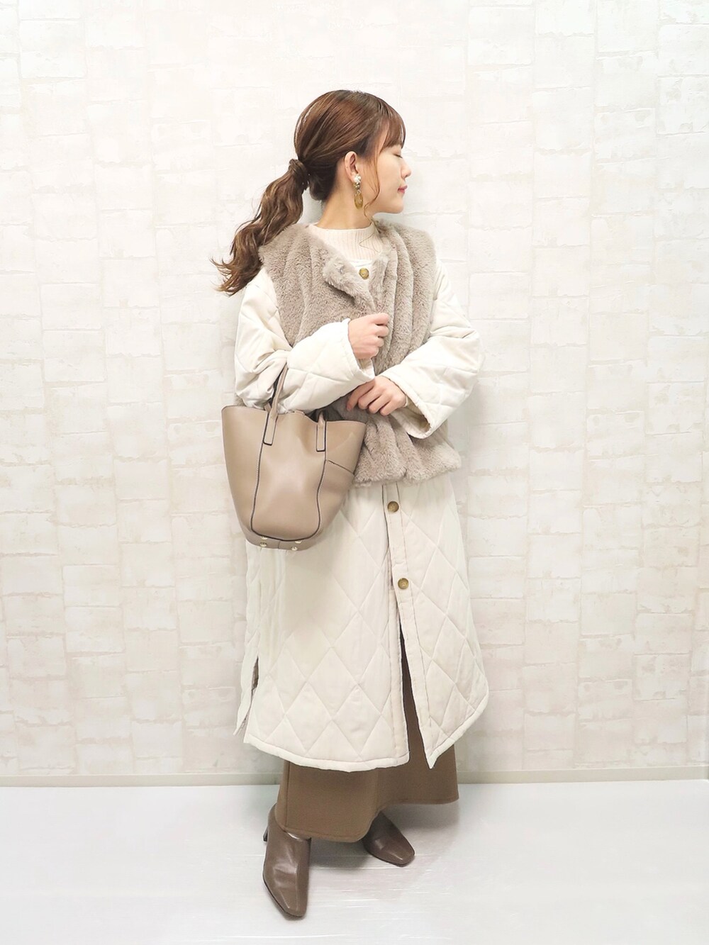 ベージュ系のその他アウター、ホワイト系のニット/セーター、ブラウン系のスカートを着用したレディースの冬コーディネートの3枚目の写真