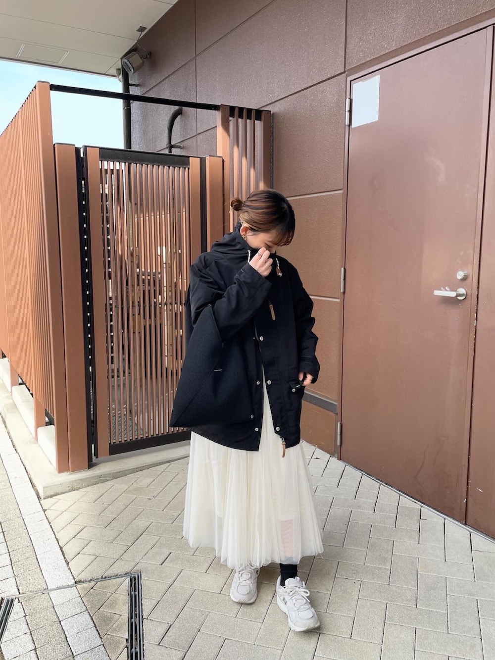 ブラック系のマウンテンパーカー、ホワイト系のTシャツ/カットソー、ホワイト系のスカートを着用したレディースの春コーディネートの2枚目の写真