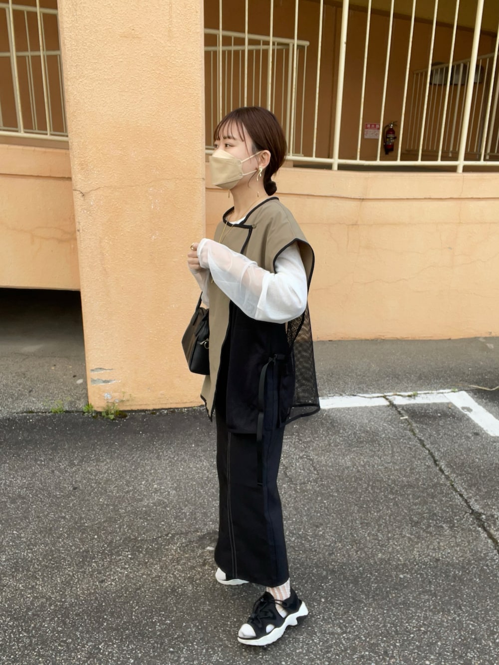 グリーン系のベスト、ブラック系のワンピース/ドレス、ホワイト系のTシャツ/カットソーを着用したレディースの春コーディネートの2枚目の写真