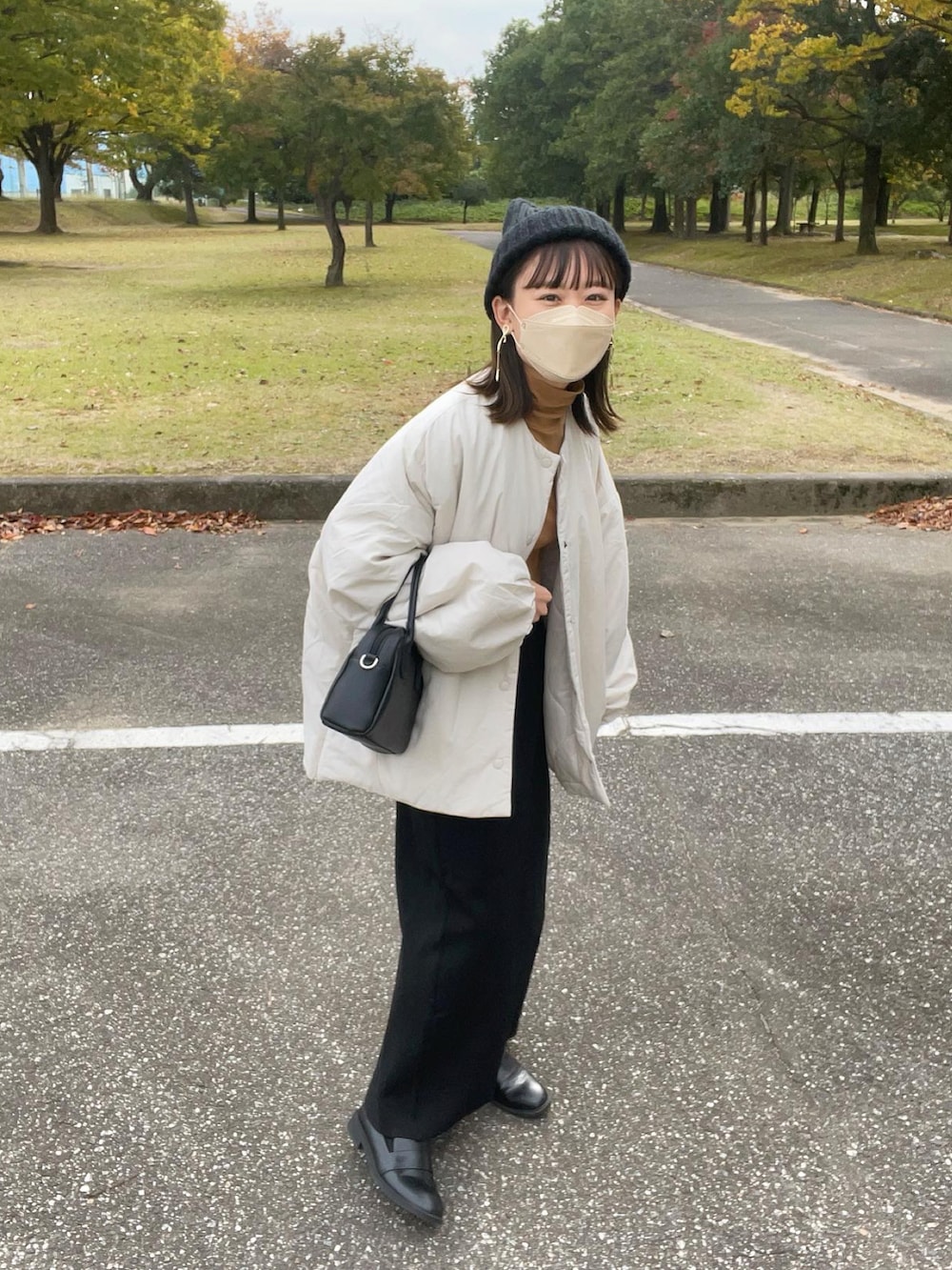 ホワイト系のダウンジャケット/コート、イエロー系のトップス、ブラック系のスカートを着用したレディースの秋コーディネートの4枚目の写真