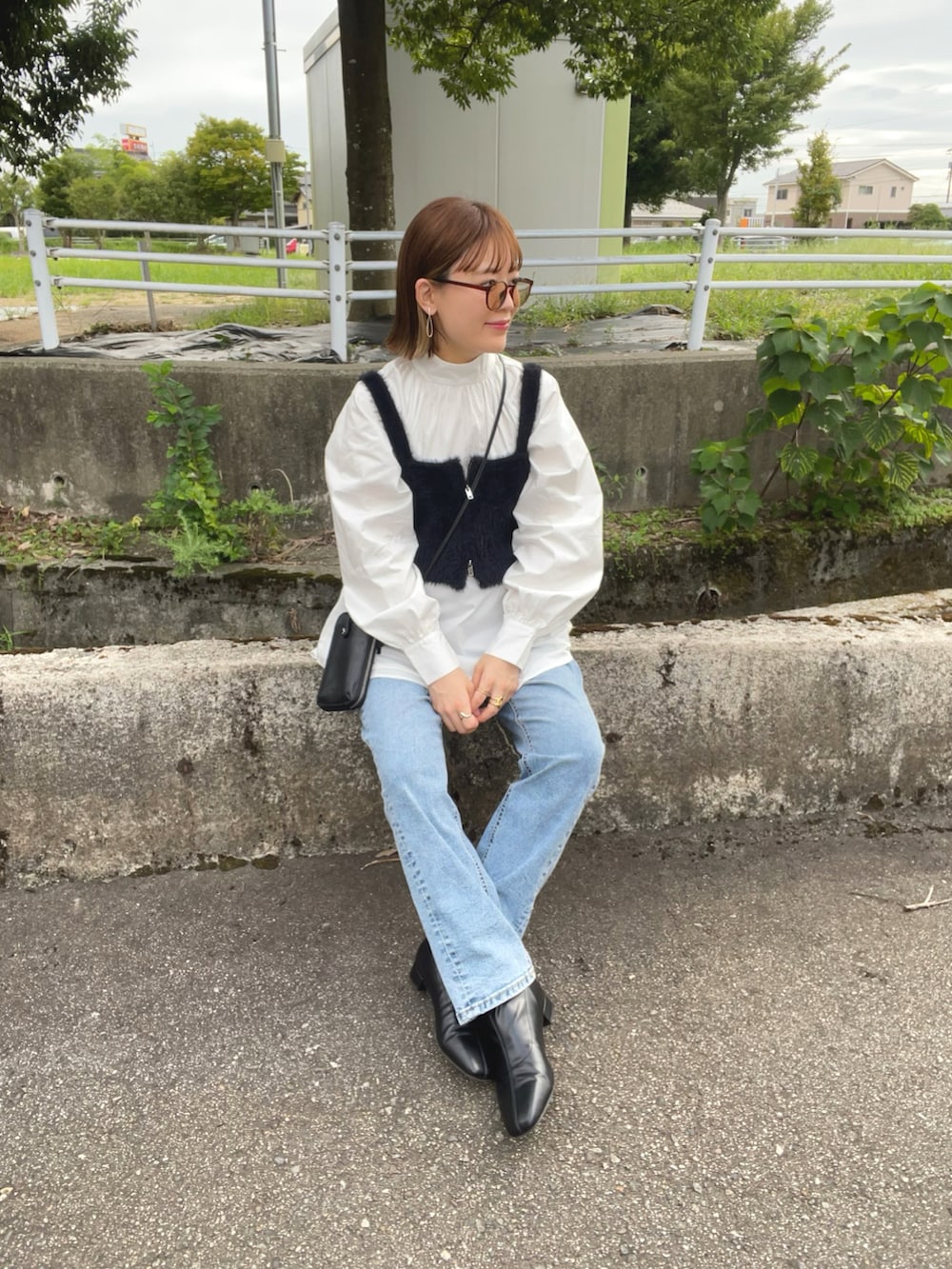 ホワイト系のシャツ/ブラウス、ブラック系のベスト、ブルー系のデニムパンツを着用したレディースの秋コーディネートの5枚目の写真