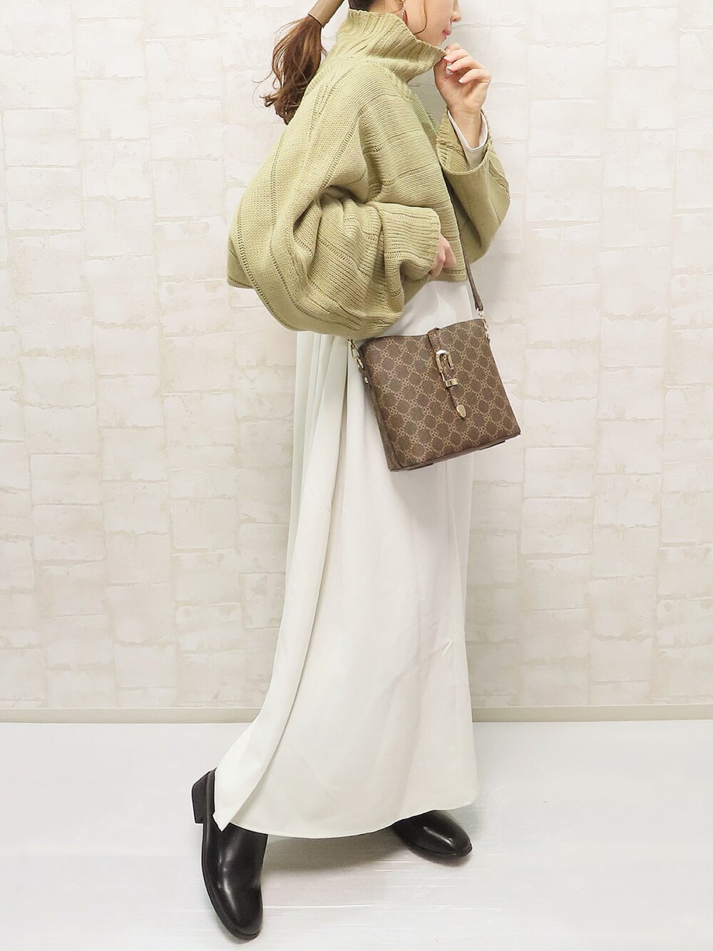 グリーン系のワンピース、ブラウン系のショルダーバッグ、ブラック系のブーツを着用したレディースの秋コーディネートの3枚目の写真