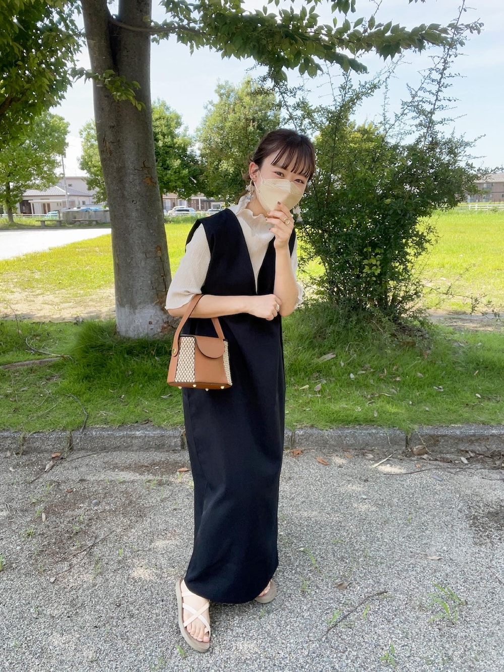 ブラック系のジャンパースカート、ホワイト系のTシャツ/カットソー、イエロー系のショルダーバッグを着用したレディースの夏コーディネートの2枚目の写真