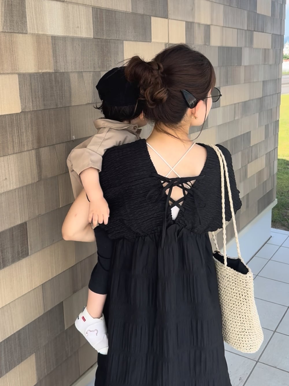 ブラック系のワンピース、ベージュ系のかごバッグ、ブラック系のサンダルを着用したレディースの夏コーディネートの2枚目の写真