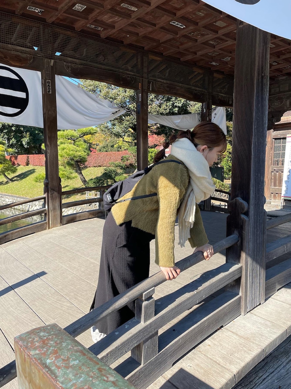 グリーン系のニット/セーター、ブラック系のバックパック/リュック、ホワイト系のスニーカーを着用したレディースの秋コーディネートの4枚目の写真