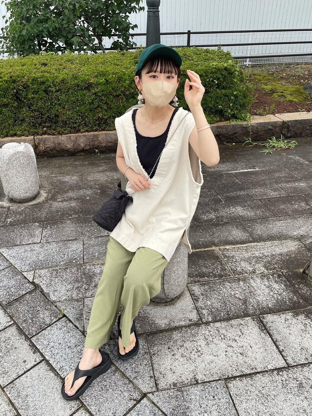 グリーン系のその他パンツ、ホワイト系のベスト、ブラック系のショルダーバッグを着用したレディースの夏コーディネートの2枚目の写真