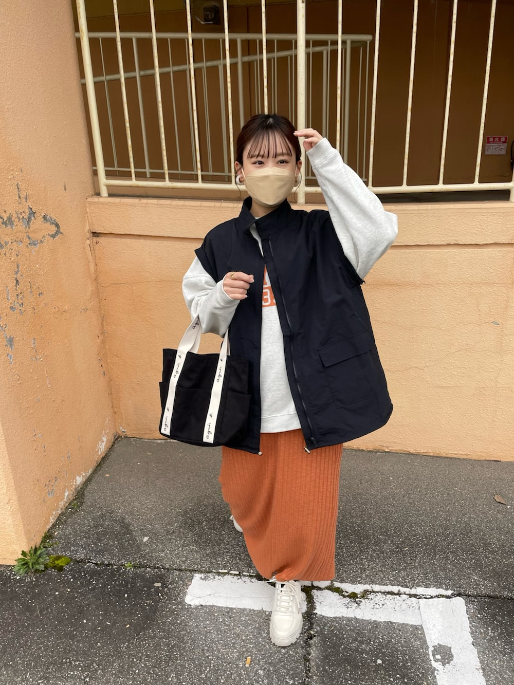 オレンジ系のスカート、ブラック系のマウンテンパーカー、グレー系のスウェットを着用したレディースの冬コーディネートの2枚目の写真