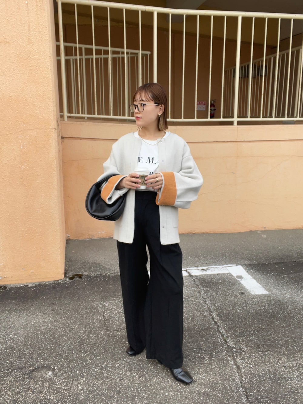 ベージュ系のノーカラーコート、ホワイト系のTシャツ/カットソー、ブラック系のパンツを着用したレディースの秋コーディネートの2枚目の写真