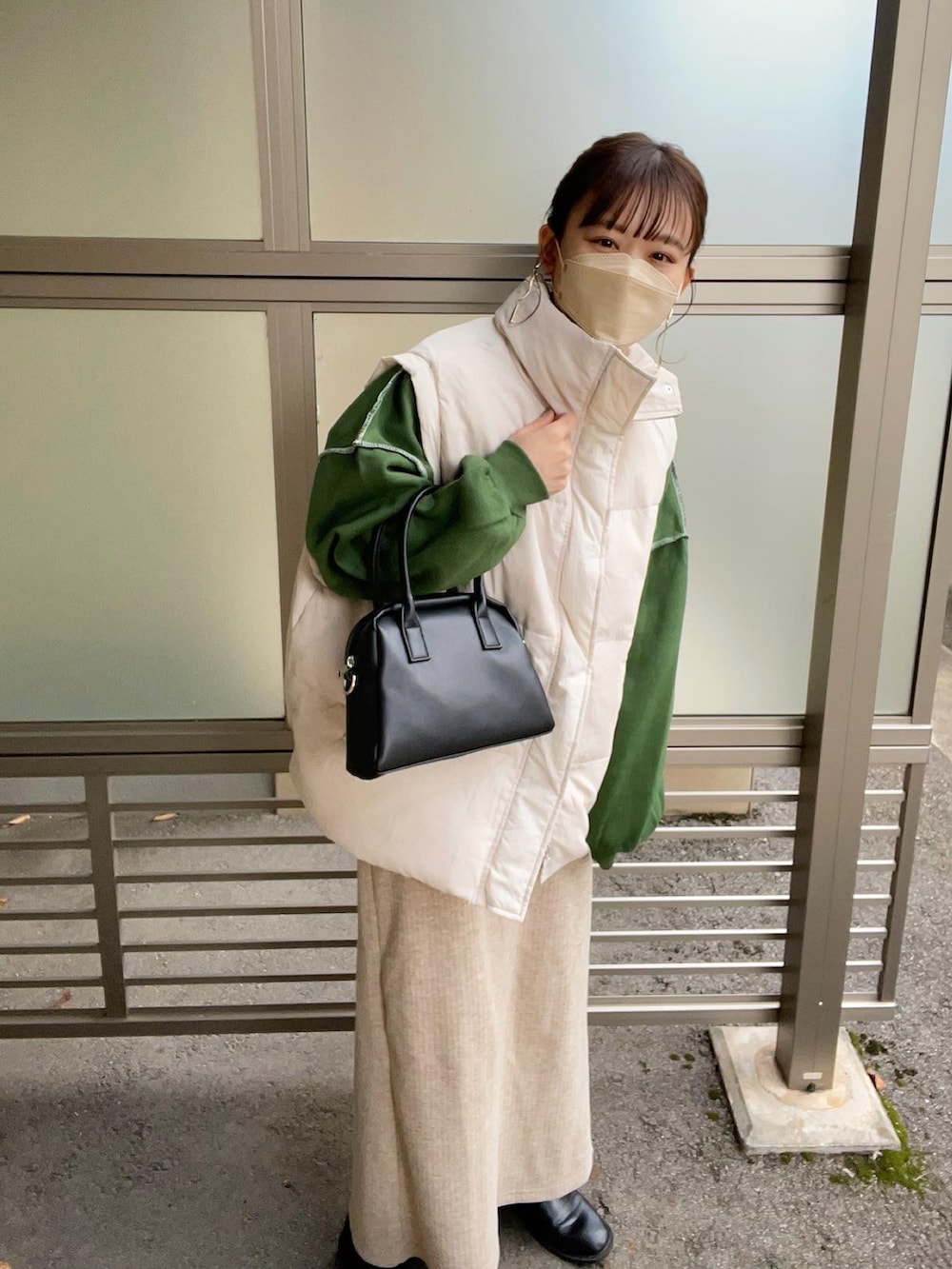 グリーン系のスウェット、ホワイト系のダウンベスト、ブラック系のボストンバッグを着用したレディースの秋コーディネートの3枚目の写真