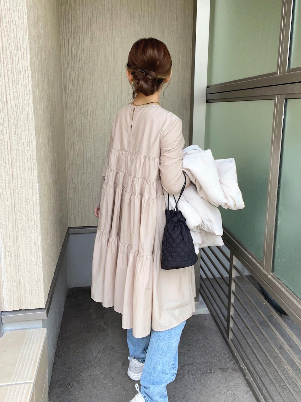 ベージュ系のワンピース、ホワイト系のダウンベスト、ブルー系のデニムパンツを着用したレディースの秋コーディネートの3枚目の写真