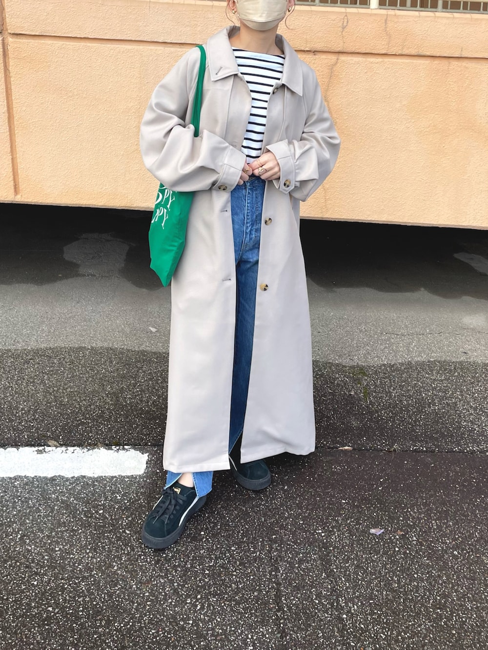 ベージュ系のトレンチコート、ホワイト系のTシャツ/カットソー、ブルー系のデニムパンツを着用したレディースの冬コーディネートの3枚目の写真