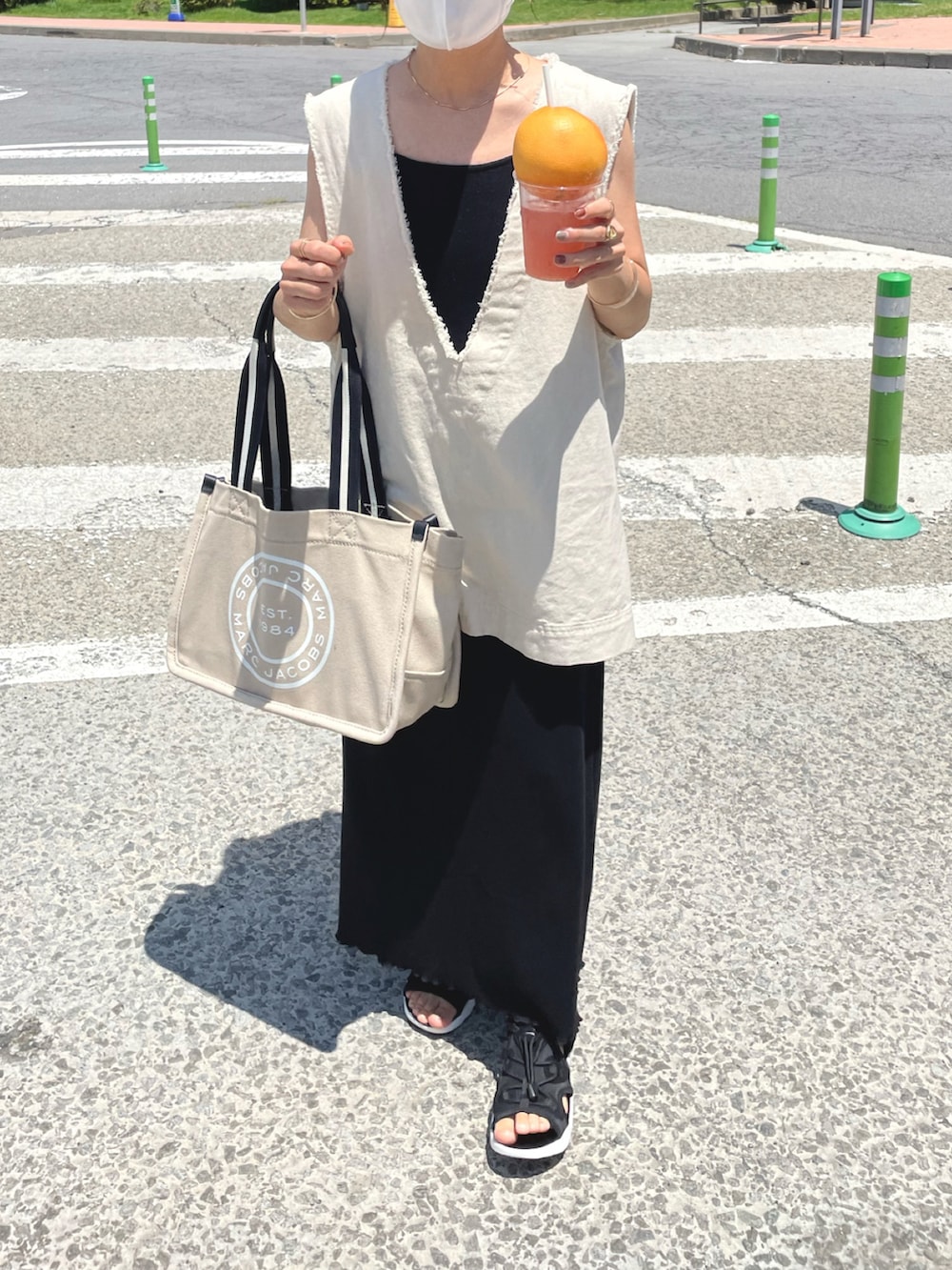 ホワイト系のベスト、ブラック系のワンピース、ベージュ系のトートバッグを着用したレディースの夏コーディネートの3枚目の写真