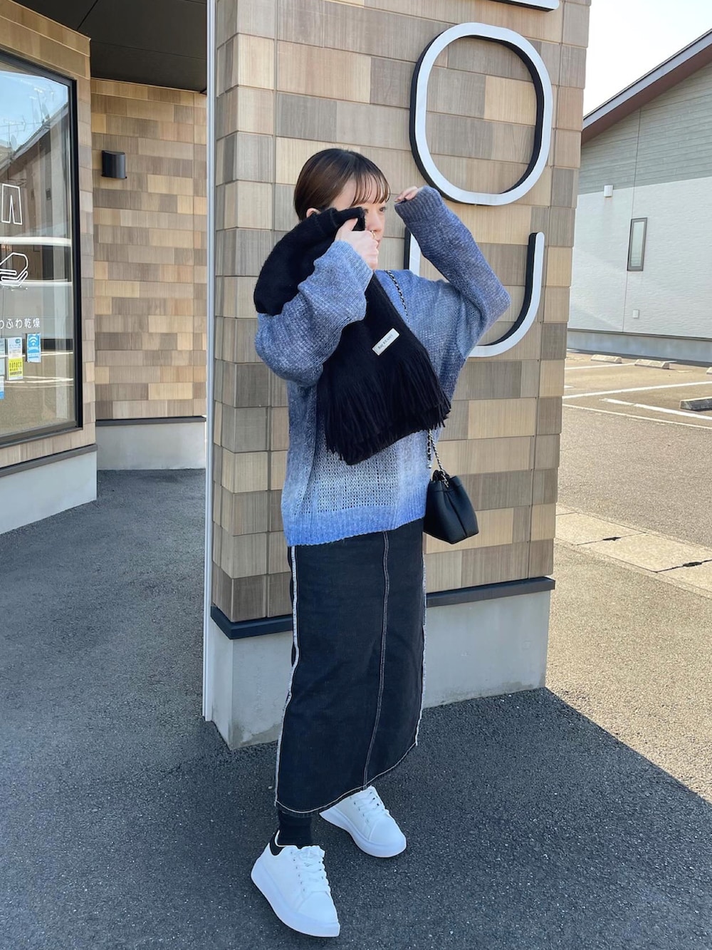ブルー系のニット/セーター、ブラック系のショルダーバッグ、ホワイト系のスニーカーを着用したレディースの冬コーディネートの2枚目の写真